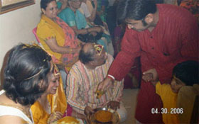 Haldi paste from the silver bowl being applied to the grooms with the doobh while the other family members enjoy the gaalis being sung on the person applying.