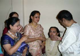 The mama -mami  and the  mother carrying on the vidhi of ' imli-ghutai' on the groom